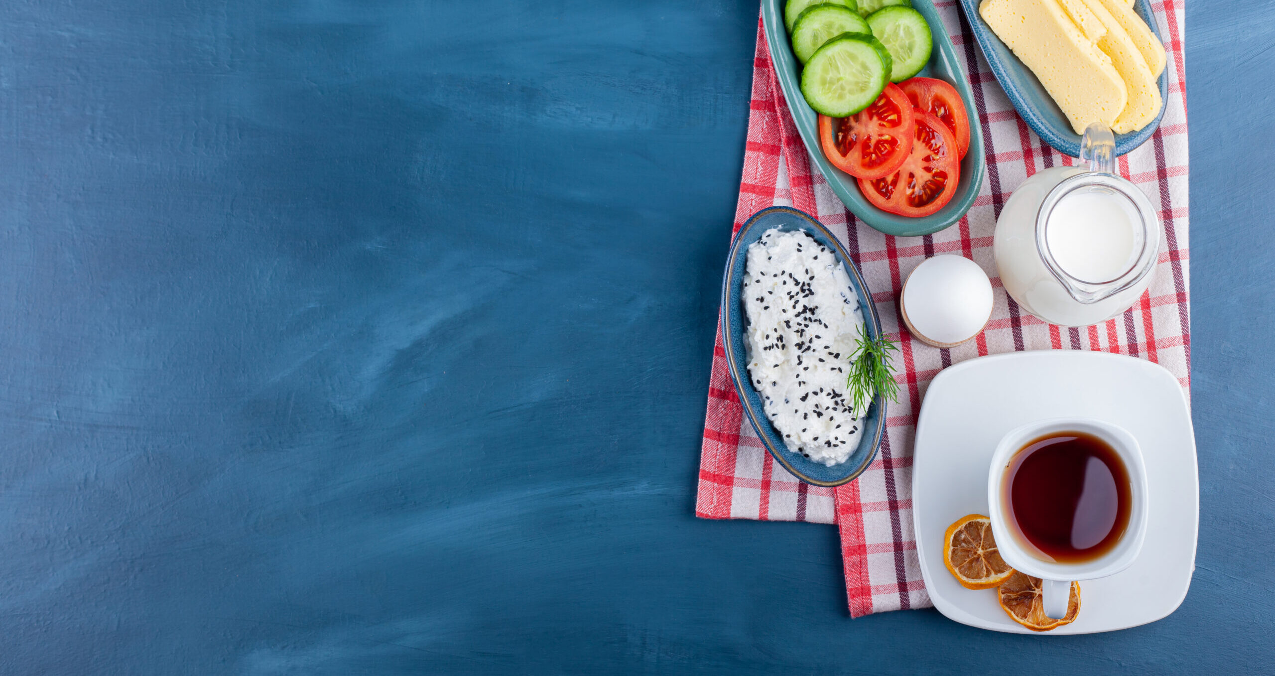 Delicious breakfast with tea, milk and cheese on blue surface. High quality photo